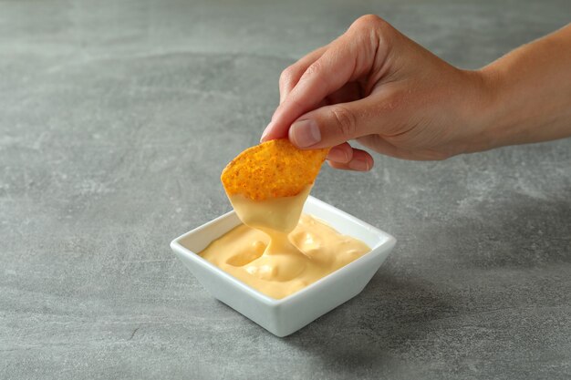 Żeńska ręka dipuje chipsy w sosie serowym, z bliska