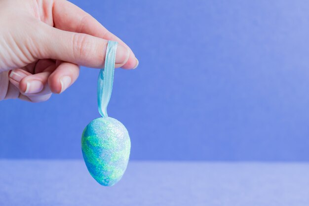 Żeńska ręka trzyma błękitnego iskrzastego Easter jajko.