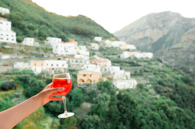 Żeńska ręka trzyma szkło z Spritz Aperol alkoholu napojem na pięknej starej włoskiej wiosce na Amalfi wybrzeżu