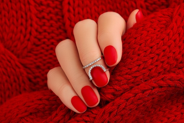 Żeńska ręka z manicure'u mienia tkaniną Czerwony matowy gwóźdź projekt