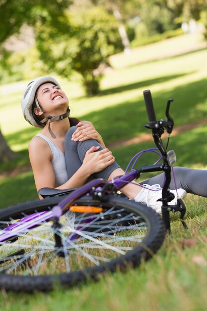 Żeński bicyclist z krzywdzi nogi obsiadanie w parku