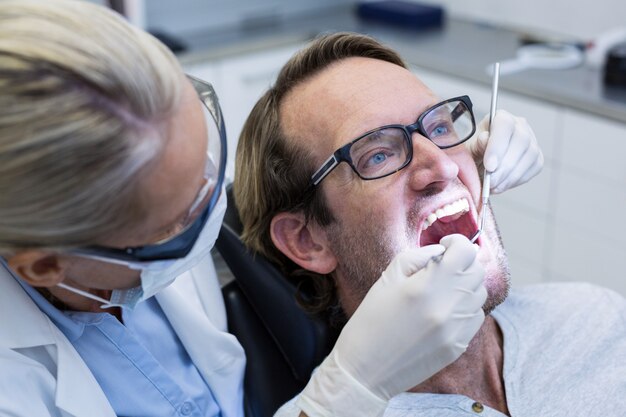 Zdjęcie Żeński dentysta egzamininuje męskiego pacjenta z narzędziami