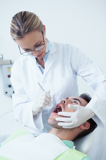 Żeński dentysta egzamininuje obsługuje zęby