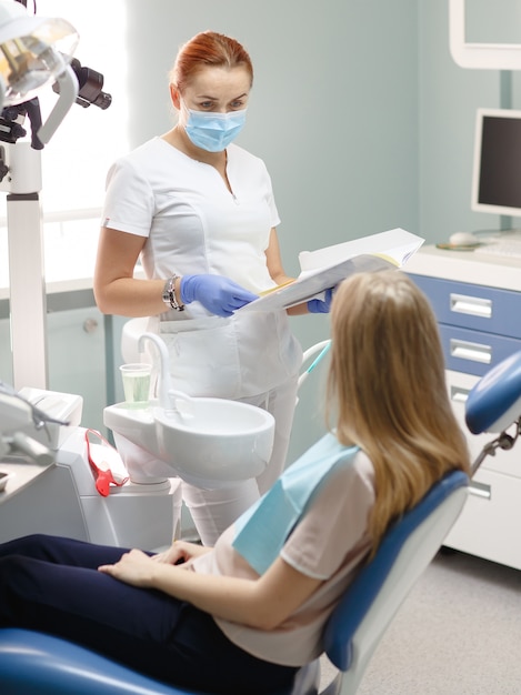 Żeński dentysta z cierpliwą kobietą opowiada przy stomatologicznym kliniki biurem