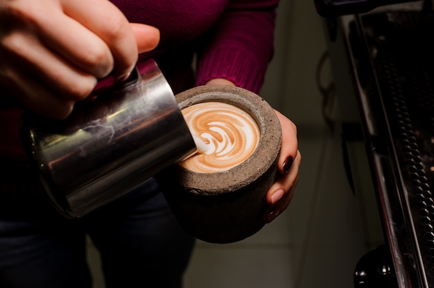 Żeńskie ręki robi latte sztuce w betonowym garnku