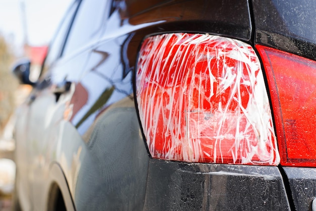 Zdjęcie zepsute czerwone tylne światło czarnego samochodu owiniętego taśmą zbliżenia
