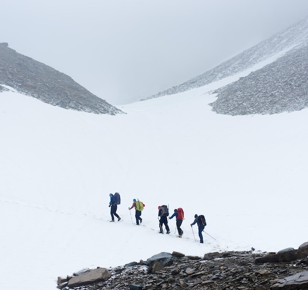 Zespół alpinistów idących po zaśnieżonej ścieżce