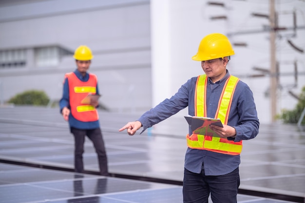 Zespół azjatyckiego inżyniera sprawdzający energię słoneczną energii ogniw słonecznych na dachu fabryki Zespół azjatyckiego pracownika pracujący instaluje system energii słonecznej z ogniwami słonecznymi do korzystania z czystej energii