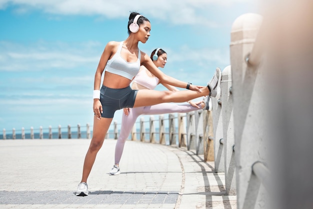Zespół biegaczy i kobiety fitness rozciągające się w celu dbania o zdrowie ciała lub dobrego samopoczucia podczas ćwiczeń kardio lub treningu maratońskiego Rozpocznij trening biegowy lub przyjaciółki przygotuj się do biegania sportowego z muzyką