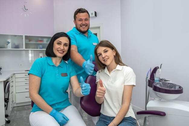 Zespół dentystów i pacjent szczęśliwie pokazujący kciuki w górę