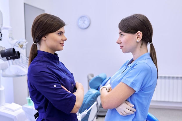 Zespół dwóch lekarzy kobiet dentystów w gabinecie stomatologicznym, koleżanki patrzą na siebie, patrzą z profilu. Koncepcja medycyny, stomatologii i opieki zdrowotnej