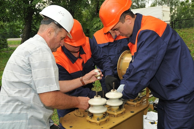 Zespół elektryków wykonuje naprawy trójfazowego transformatora olejowego zasilania elektrycznego