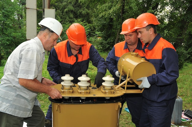 Zespół Elektryków Wykonuje Naprawy Trójfazowego Transformatora Olejowego Zasilania Elektrycznego