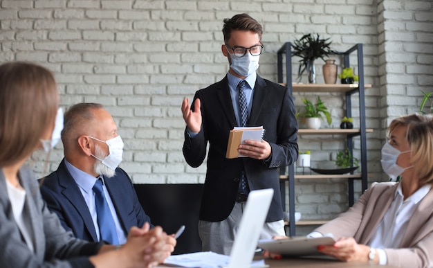 Zespół firmy w maskach ochronnych pracuje w biurze.