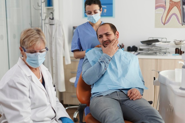 Zespół lekarzy stomatologów wyjaśniający próchnicę choremu pacjentowi z bólem zęba, omawiając ekspertyzę lekarską podczas konsultacji stomatologicznej w gabinecie stomatologicznym. Koncepcja usług medycznych