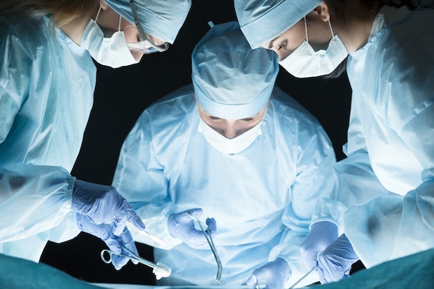 Zespół medyczny wykonujący operację. Grupa chirurgów przy pracy na sali operacyjnej