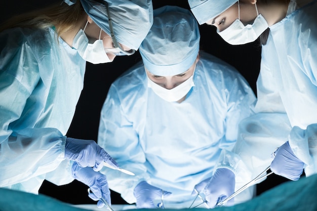 Zdjęcie zespół medyczny wykonujący operację. grupa chirurgów przy pracy na sali operacyjnej