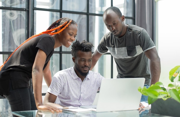 Zespół młodych Afrykańczyków w biurze pracujący na laptopie