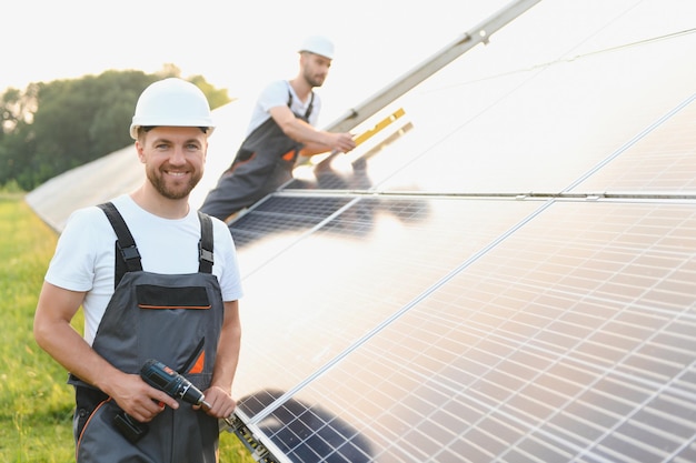 Zespół pracowników z panelem słonecznym Zespół pracowników pomyślnie zainstalował panel słoneczny na polu farmy słonecznej