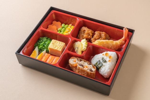 Zestaw bento z kulką ryżową, krewetkami, sushi i warzywami