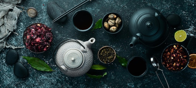 Zestaw czarnej zielonej herbaty owocowej i ziołowej na czarnym tle kamienia Herbata w czajniczku i filiżance Widok z góry wolne miejsce na tekst