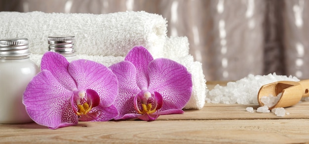 Zestaw do zabiegów spa z balsamami do skóry, kwiatami orchidei, solą do kąpieli i białymi ręcznikami