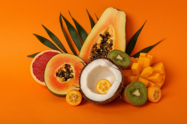 Zestaw egzotycznych owoców na pomarańczowym tle.