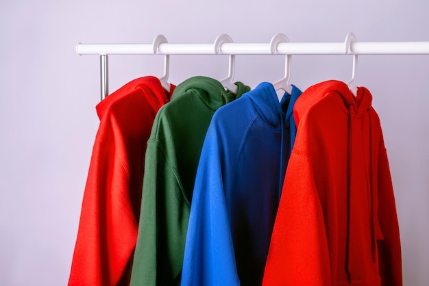 Zestaw kolorowych bluz z różnych tkanin. Wisi na drążku wieszaka na ubrania