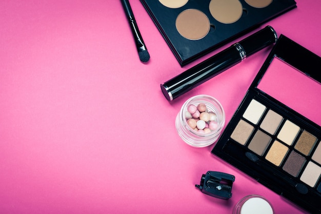 Zestaw kolorowych kosmetyków na różowym stole