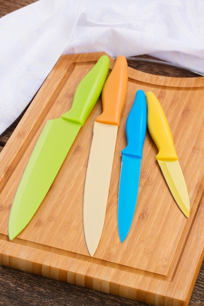 Zestaw kolorowych noży na drewnianej desce do krojenia