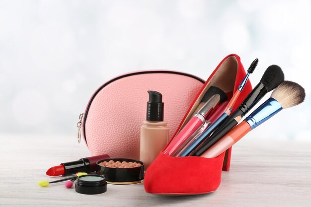 Zestaw makijażu z czerwonymi szczotkami do butów i kosmetykami na jasnym tle