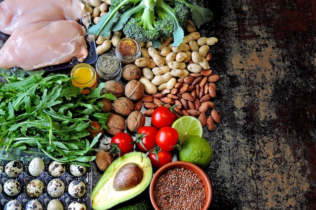 Zdjęcie zestaw produktów diety ketonowej o niskiej zawartości węglowodanów. zielone warzywa, orzechy, filet z kurczaka, nasiona lnu, jaja przepiórcze, pomidory koktajlowe.