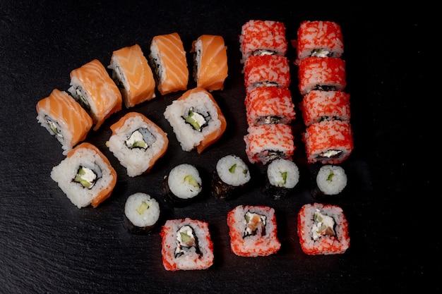 Zestaw rolek sushi na czarnej powierzchni łupków jedzenie ryba philadelphia japoński łosoś pyszne sushi ryż ogórek posiłek tradycyjne wasabi świeże zdrowe smakosz surowy kuchnia