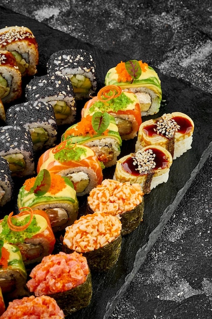 Zdjęcie zestaw różnych rolek sushi na czarnej tablicy asortyment japońskich sushi z krewetkami z łososia i węgorza