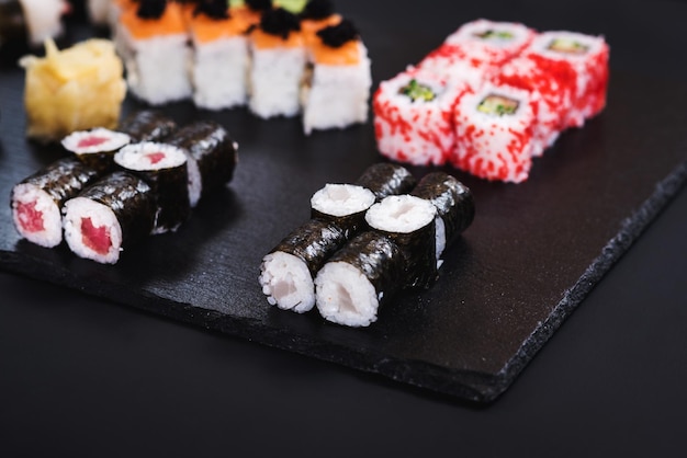 Zestaw różnych rolek sushi z kawiorem na czarnym tle