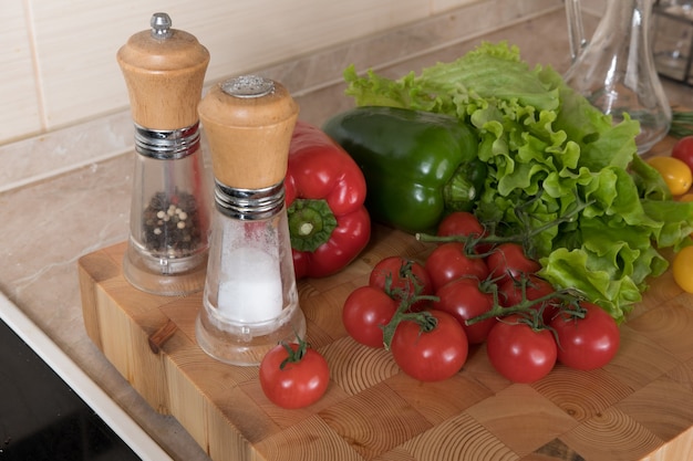 Zdjęcie zestaw różnych warzyw na desce do krojenia w kuchni. pojęcia zdrowego odżywiania. składniki sałatki, pomidory, papryka, przyprawy