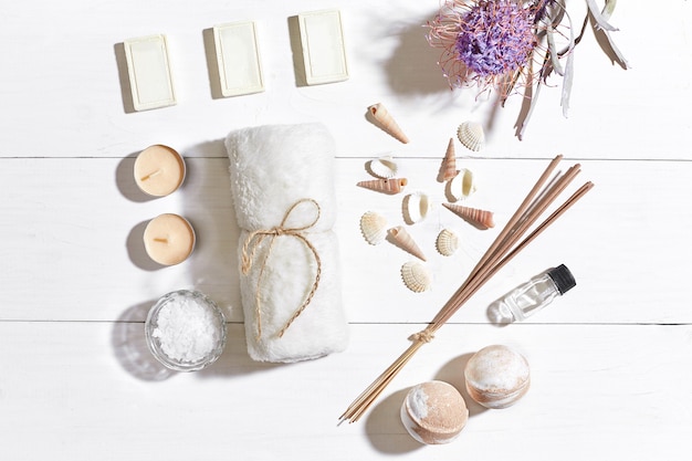 Zdjęcie zestaw spa z mydłem i ręcznikiem z olejkiem eterycznym z soli morskiej ozdobionym suchym kwiatem na białym drewnianym tle