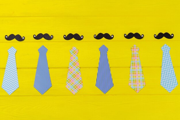 Zestaw stylowych męskich krawatów i wąsów żółte drewniane biurko