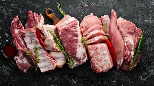 Zestaw surowego mięsa Mięso wieprzowe na czarnym kamiennym tle z przyprawami i ziołami Widok z góry Styl rustykalny