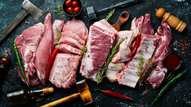 Zestaw surowego mięsa Mięso wieprzowe na czarnym kamiennym tle z przyprawami i ziołami Z góry widok w stylu rustykalnym