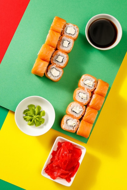 Zestaw sushi na kolorowym jasnym tle podawany z sosem sojowym wasabi i gingerxA