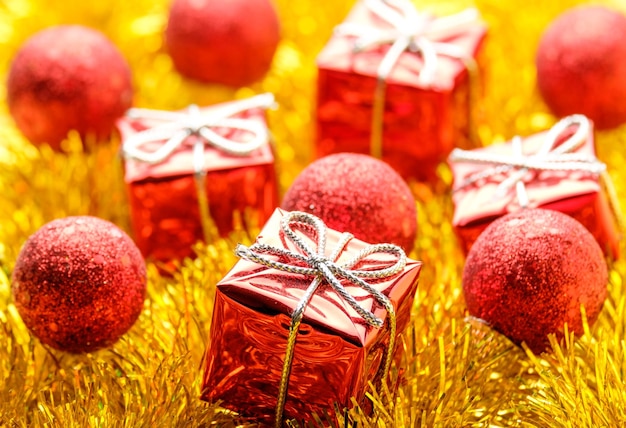 Zestaw świątecznych dekoracji czerwonych kulek i prezentów nad żółtą girlandą