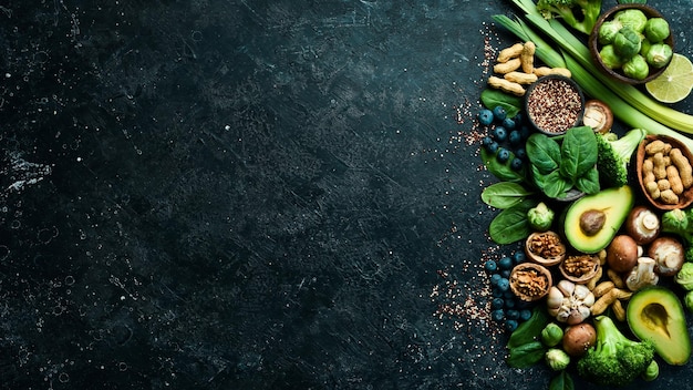 Zdjęcie zestaw zdrowej żywności zielone warzywa awokado brokuły orzechy grzyby jagody i szpinak na czarnym tle kamienia widok z góry kopiowanie miejsca