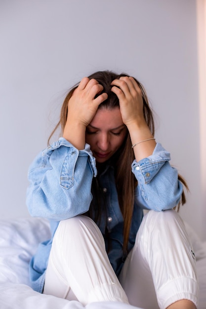 Zestresowana młoda kobieta trzymająca głowę w dłoniach przygnębiona problemami finansowymi siedząca na kanapie w salonie