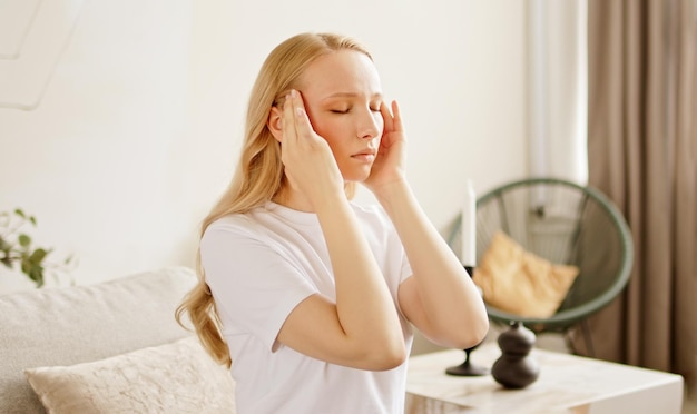 Zdjęcie zestresowana niezdrowa kobieta czująca się zmęczona ma okropny silny ból głowy.