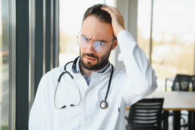 Zestresowany lekarz płci męskiej Połowa dorosłego lekarza płci męskiej pracująca przez wiele godzin Przepracowany lekarz w swoim biurze Nawet lekarze nie są zwolnieni z wypalenia zawodowego