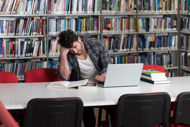 Zestresowany uczeń w liceum siedzący przy biurku biblioteki