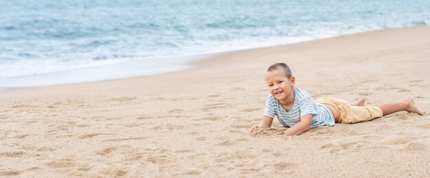 Zdjęcie zewnątrz portret małego chłopca ładny r. na piaszczystej plaży. panorama