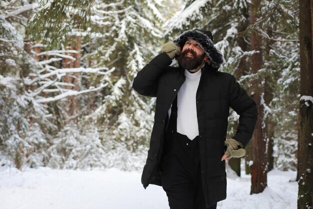 Zewnątrz portret przystojny mężczyzna w płaszcz i szalik. Brodaty mężczyzna w zimowym lesie.