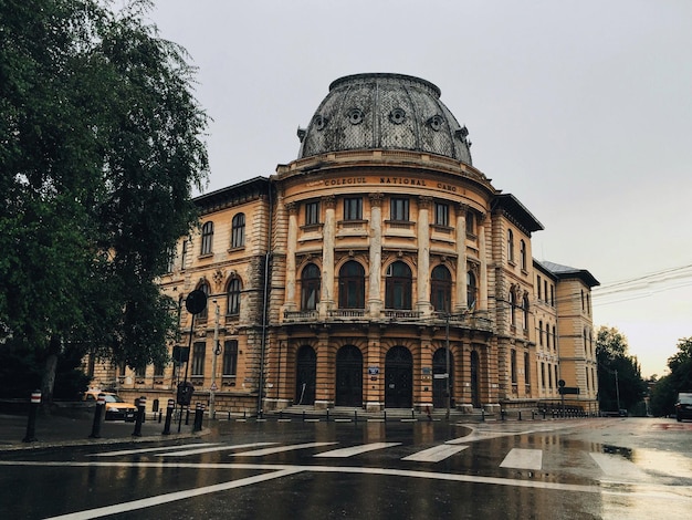 Zewnętrzna część Carol I National College na mokrej drodze na jasnym niebie